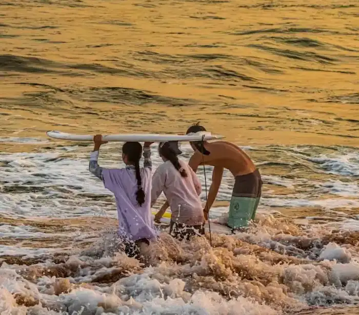 باشگاه موج‌سواری رمین - دو دختر و یک پسر در ساحل با تخته موج‌سواری